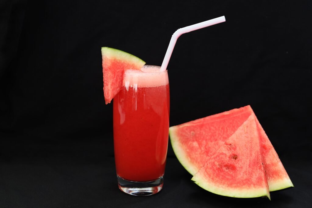 Close-up of a refreshing watermelon juice with a straw and watermelon slices.