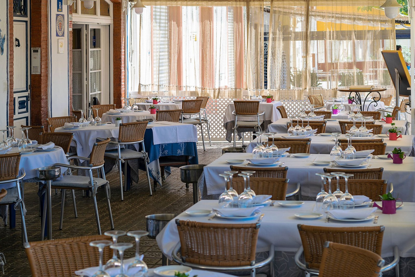 Charming outdoor dining area with neatly set tables in Sitges, Spain, bathed in natural light.