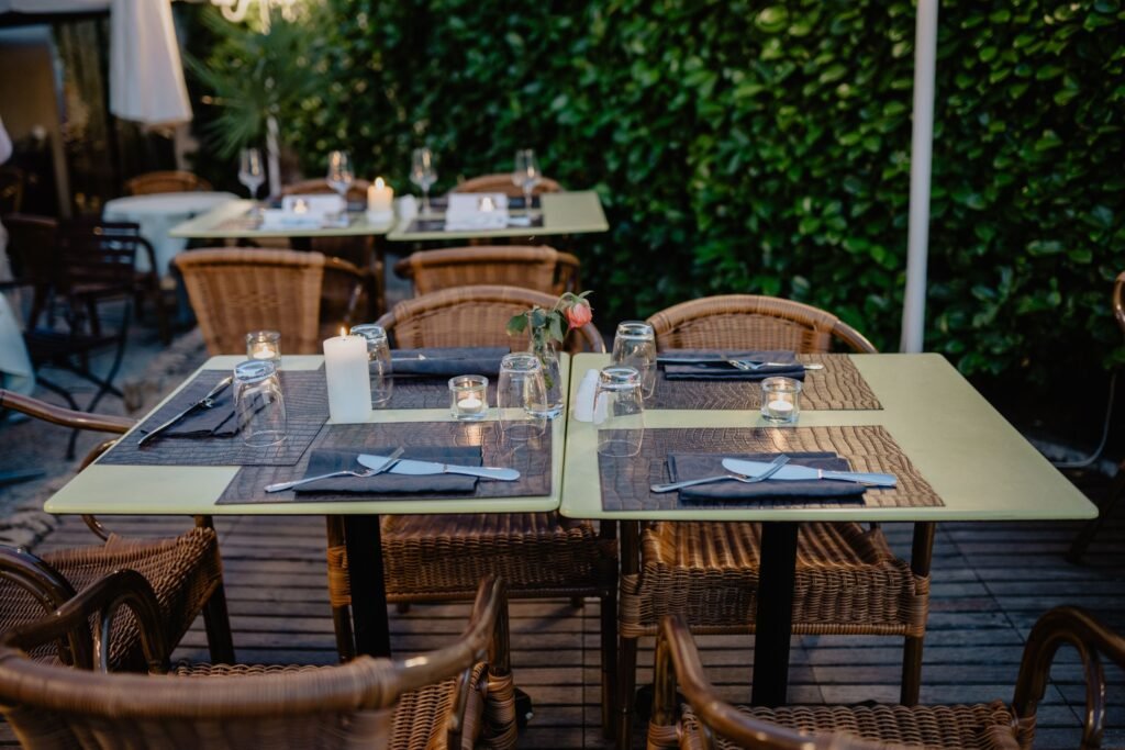Intimate outdoor dining setting with wicker chairs and candlelit tables on a charming terrace.