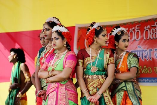 About Us Indian dancers in traditional attire performing at a cultural festival outdoors.