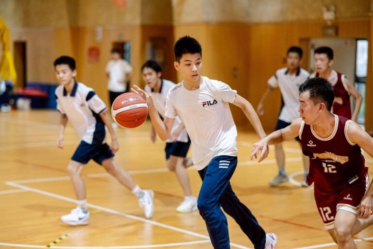 About Us Teen boys playing competitive basketball indoors, showcasing teamwork and agility.
