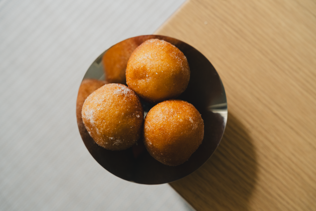 Top-down view of sugar-coated quark balls in a brown bowl on wooden table.