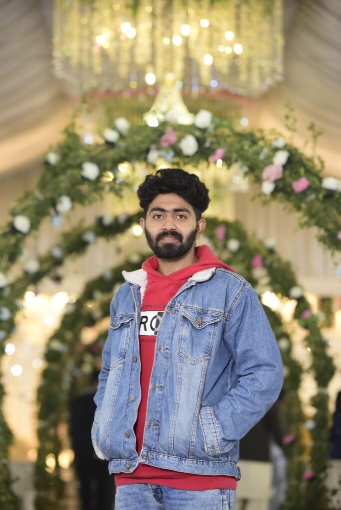 Portrait of a young South Asian man in stylish denim with floral decor backdrop in Pakistan.