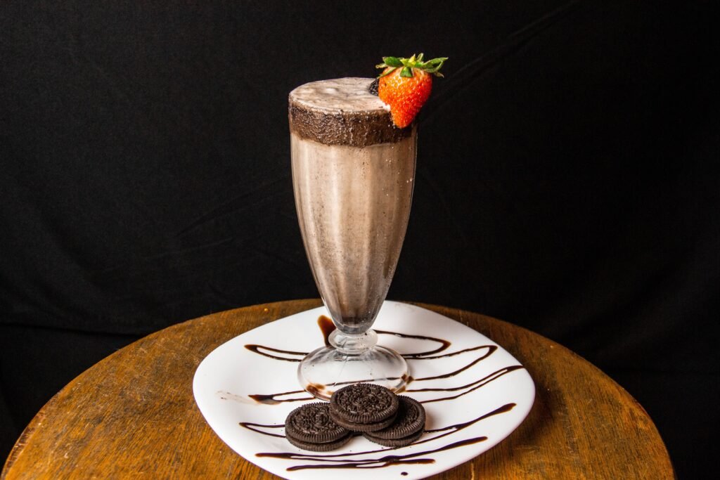 Indulge in a creamy chocolate milkshake garnished with a fresh strawberry and served with cookies.