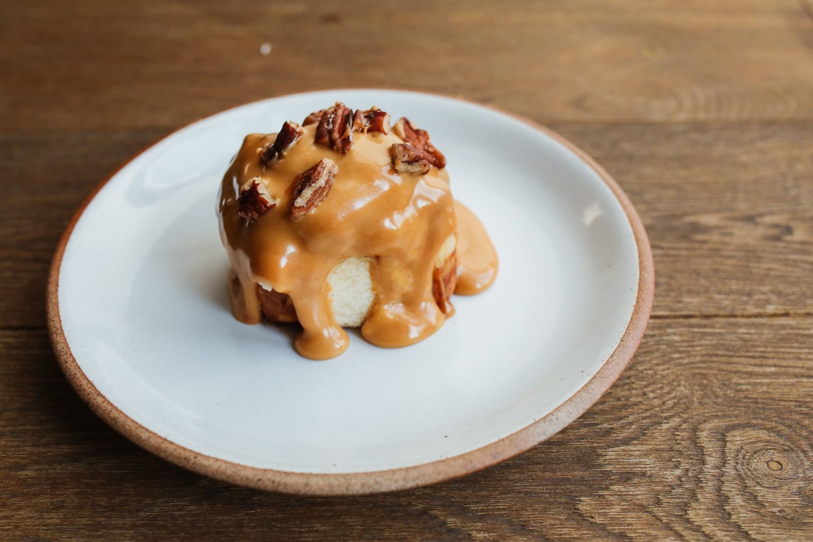A delicious caramel pecan cinnabon on a rustic-style plate, perfect dessert.