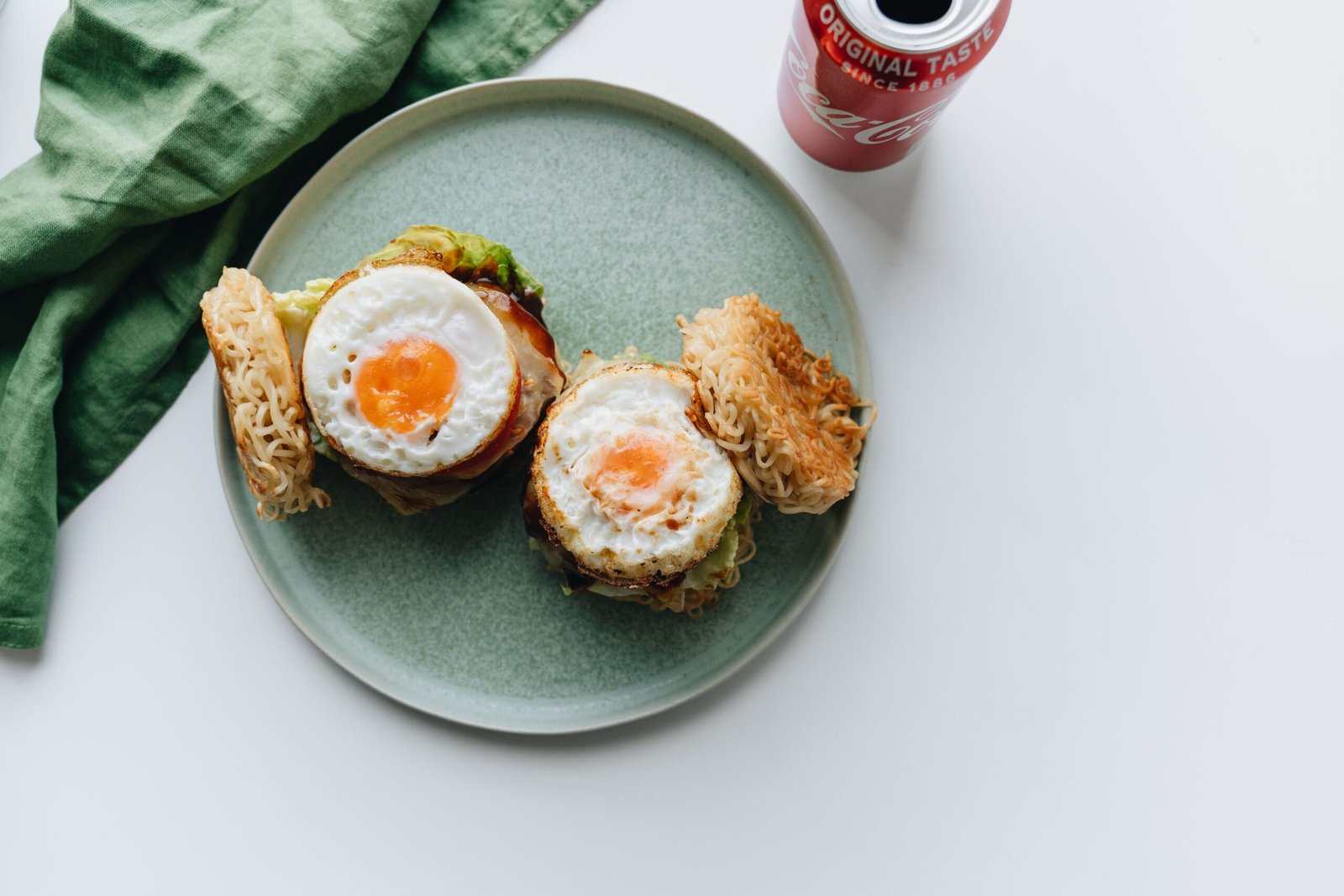 Delicious ramen burgers topped with fried eggs and served with a refreshing soda drink.