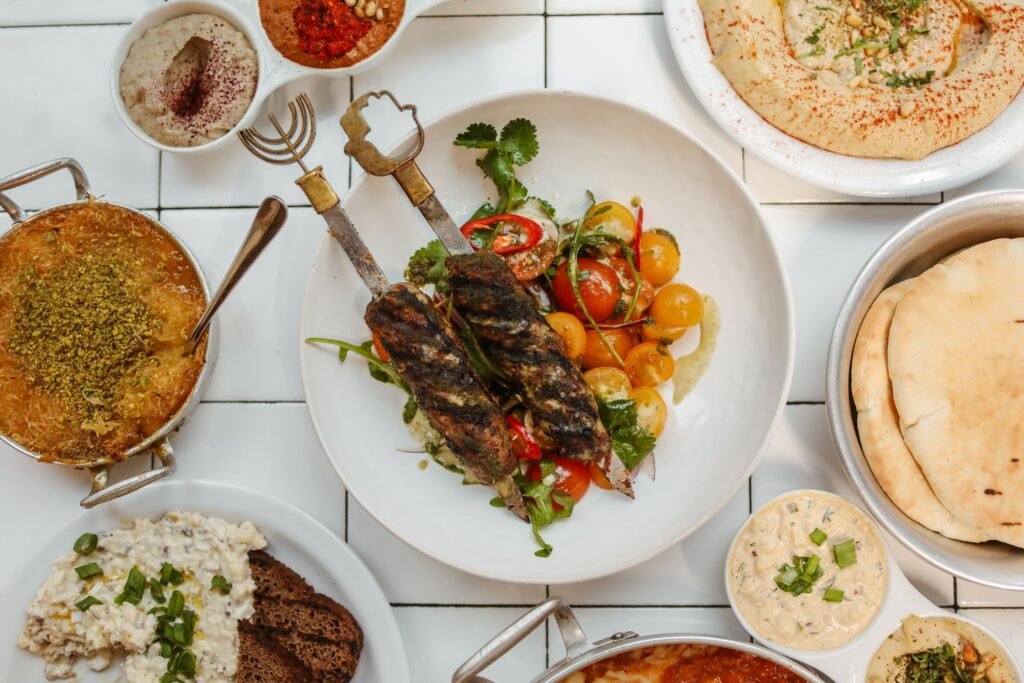 Delicious Middle Eastern spread featuring kebabs, dips, hummus, and traditional breads on a white ceramic background.