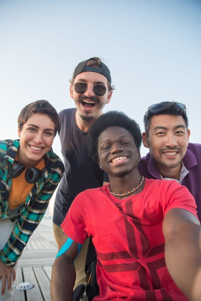 Diverse group of friends smiling and posing together outdoors under a clear sky.